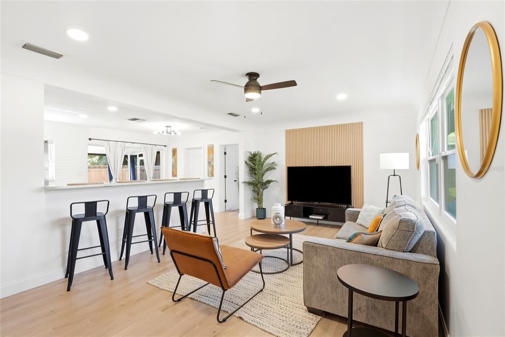 A living room features light wood floors, a television on a slatted wall, and bar seating — 2117 N HERCULES AVENUE, CLEARWATER, FL