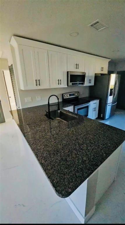 A kitchen features white cabinets, a dark granite countertop, and stainless steel appliances — 2459 17TH AVENUE S, ST PETERSBURG, FL