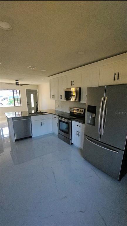 A kitchen features white cabinets, stainless steel appliances, and light-colored marble-look tile flooring — 2459 17TH AVENUE S, ST PETERSBURG, FL