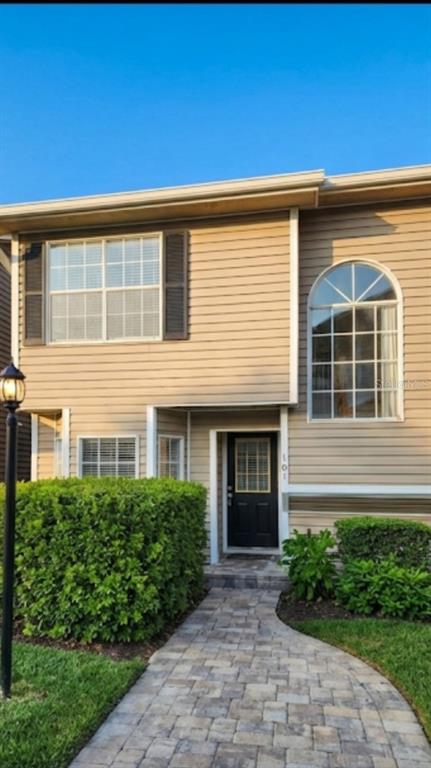 A two-story house with tan siding, a black front door, and a stone walkway — 6050 SCOTCHWOOD GLEN UNIT 105, ORLANDO, FL