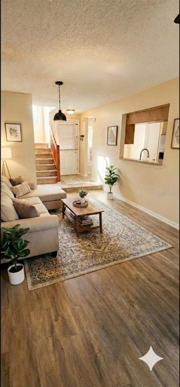 A living room features light-colored wood flooring, a beige sofa, a wooden coffee table, and stairs — 6050 SCOTCHWOOD GLEN UNIT 105, ORLANDO, FL