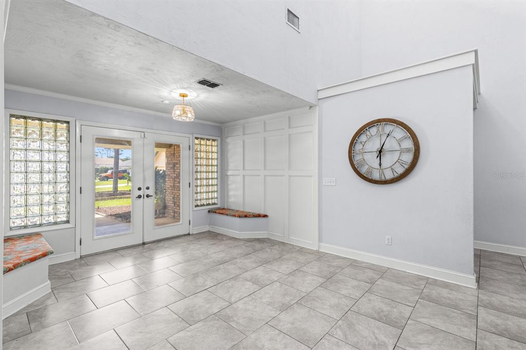 An entryway with tile flooring, glass block windows, built-in benches, and a large wall clock — 82 KINGSLEY PLACE, ORMOND BEACH, FL