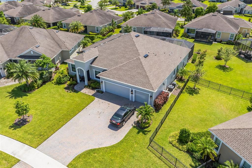 An aerial view shows a single-story house with a paved driveway and a two-car garage — 7356 MILLBROOK AVENUE, MELBOURNE, FL