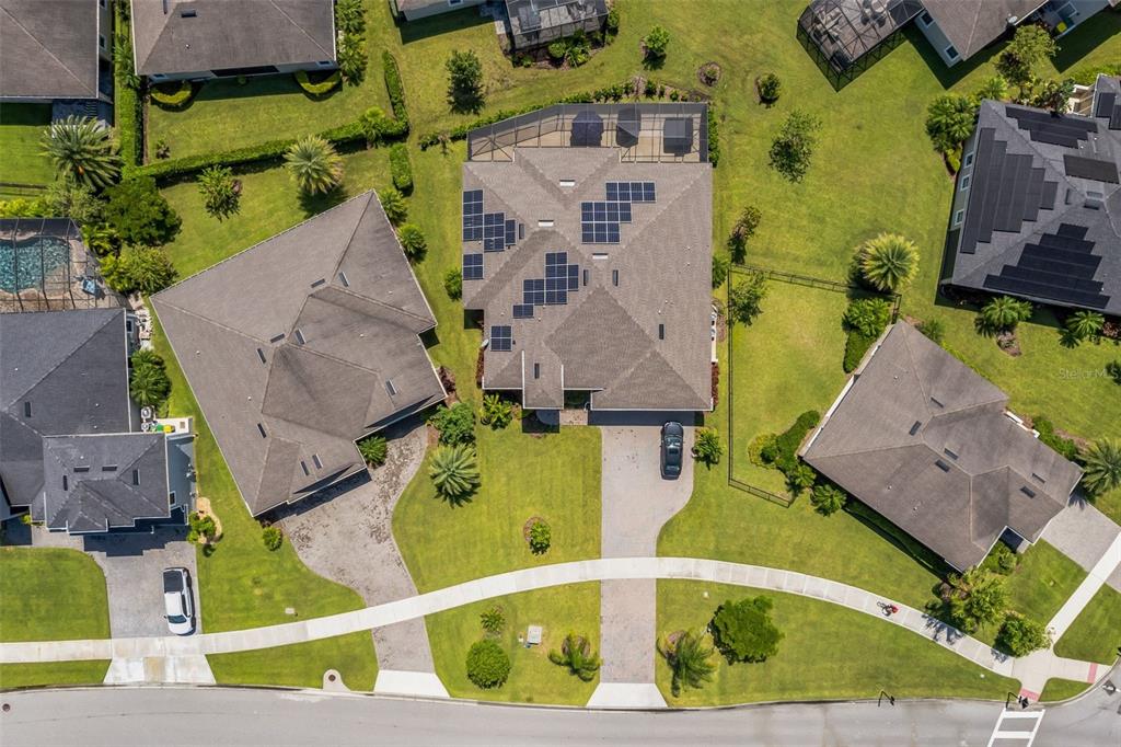 An aerial view shows a suburban house with solar panels on its roof and a pool — 7356 MILLBROOK AVENUE, MELBOURNE, FL
