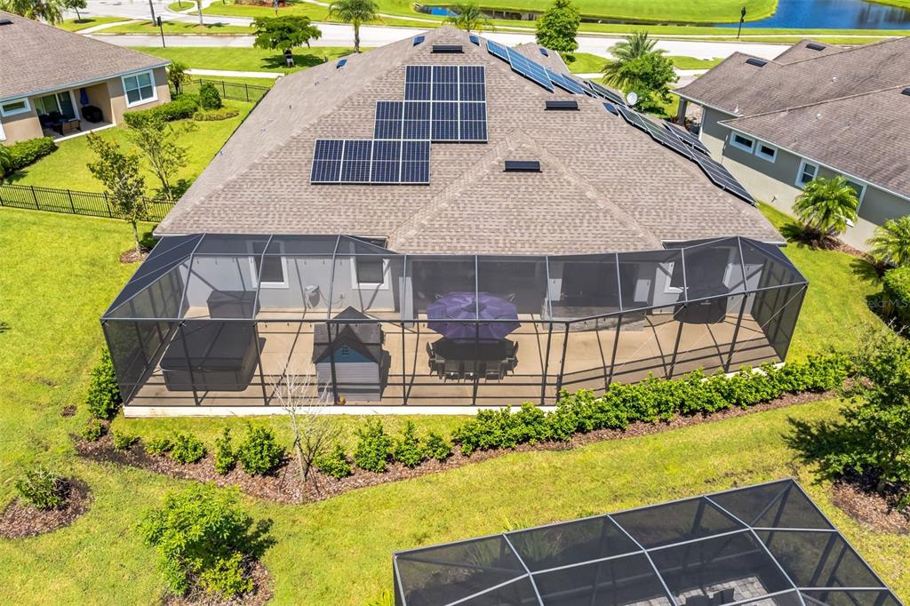 An aerial view shows a house with solar panels on the roof and a screened-in patio — 7356 MILLBROOK AVENUE, MELBOURNE, FL