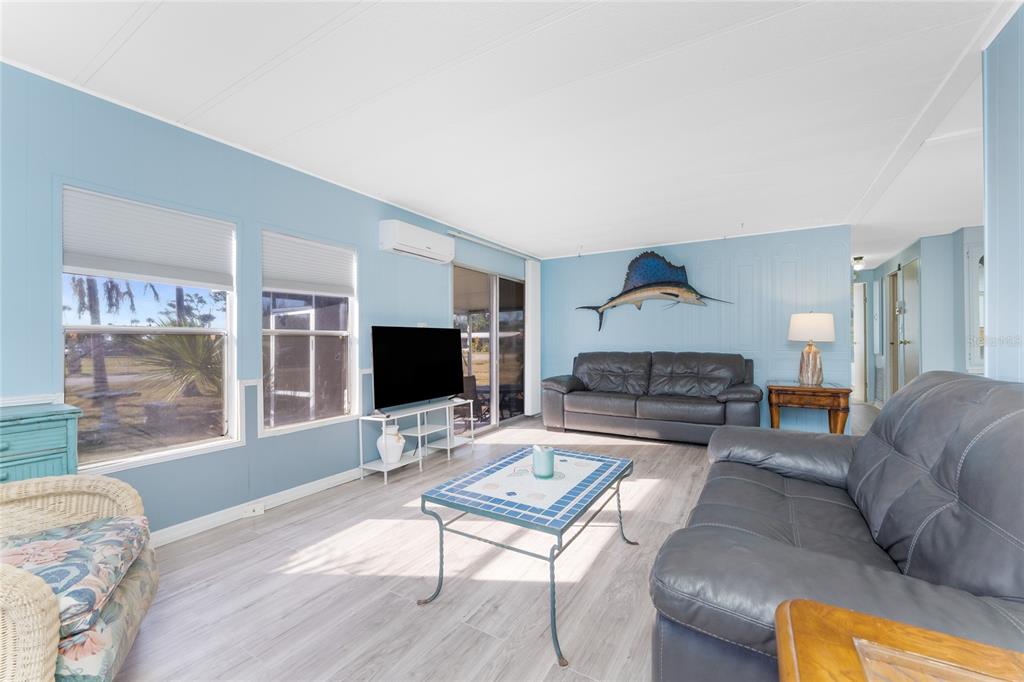 A living room features light blue walls, wood-look flooring, two leather sofas, and a fish mount — 3111 WATERSIDE DRIVE, ENGLEWOOD, FL