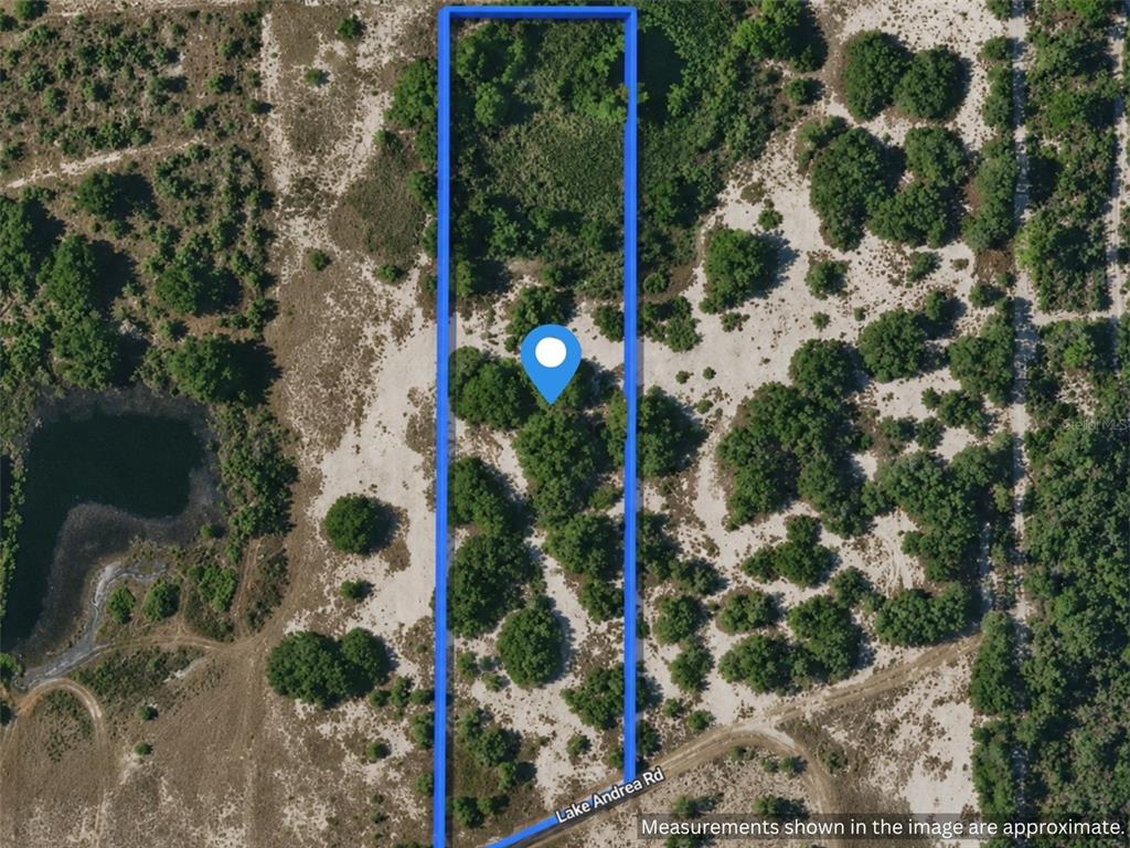 An aerial view shows a rectangular plot of land outlined in blue near a dirt road — LAKE ANDREA RD, BABSON PARK, FL