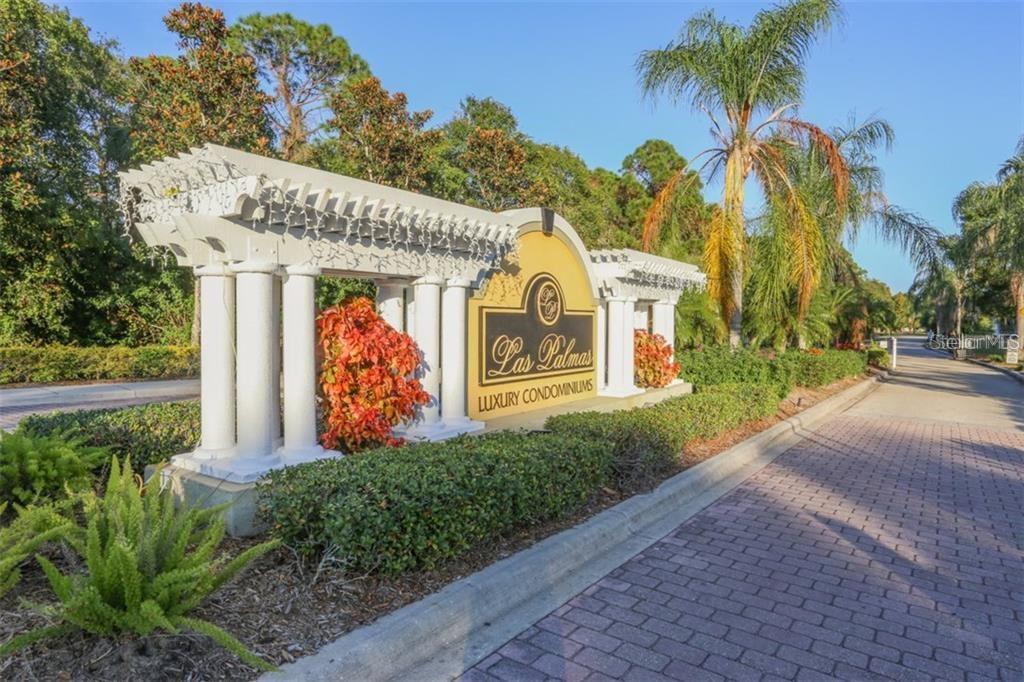 A white decorative entrance sign for Las Palmas Luxury Condominiums stands beside a paved road — 5655 BENTGRASS DRIVE UNIT 9-117, SARASOTA, FL