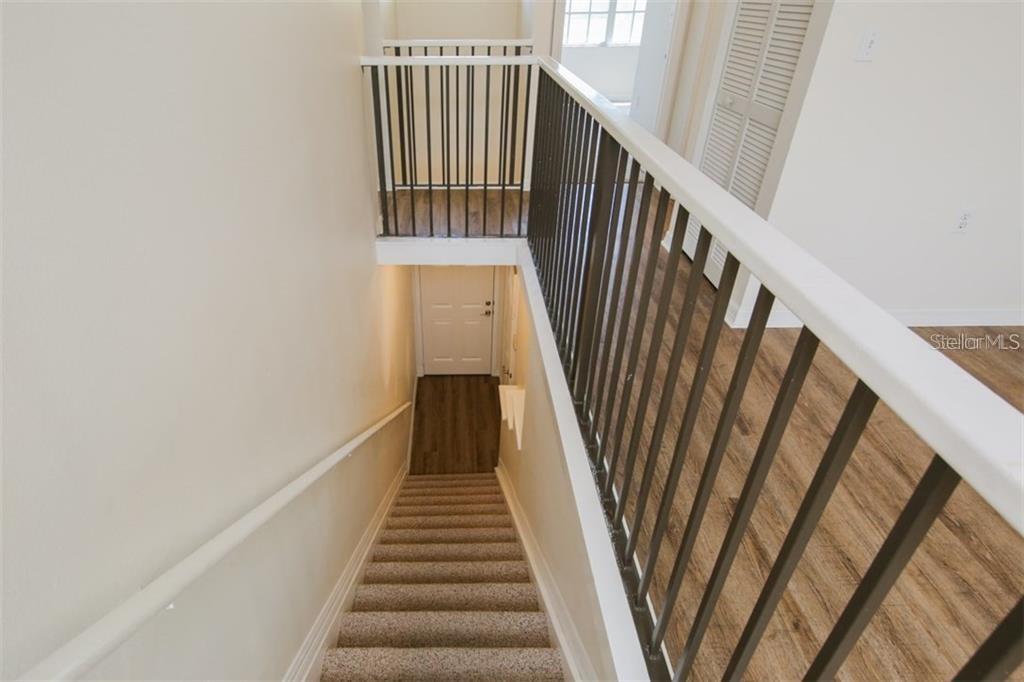 A kitchen with granite countertops and pendant lights overlooks a living area with wood flooring — 5655 BENTGRASS DRIVE UNIT 9-117, SARASOTA, FL