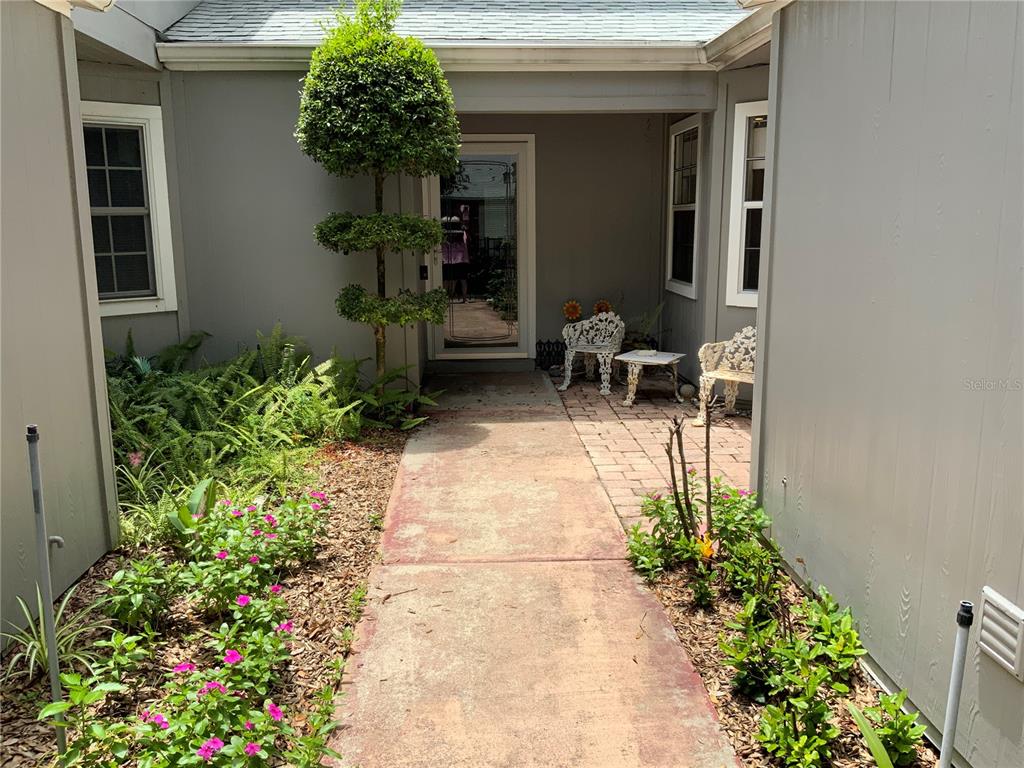 A paved walkway leads to the front entrance of a house with a small patio — 618 MAPLE OAK CIRCLE UNIT 112, ALTAMONTE SPRINGS, FL