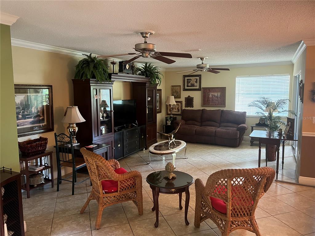 A living room features wicker chairs, a brown sofa, a media center, and tile flooring — 618 MAPLE OAK CIRCLE UNIT 112, ALTAMONTE SPRINGS, FL