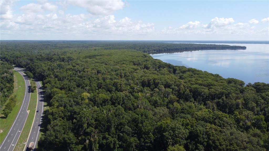 An aerial view of a dense forest bordering a large lake next to a highway — SE HAWTHORNE ROAD, GAINESVILLE, FL