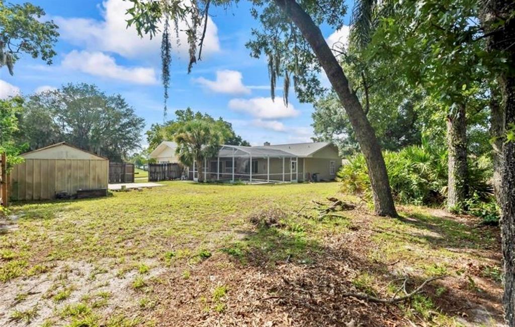 A backyard view of a house with a screened-in porch and a detached storage shed — 2831 ASCOT LANE, DELTONA, FL