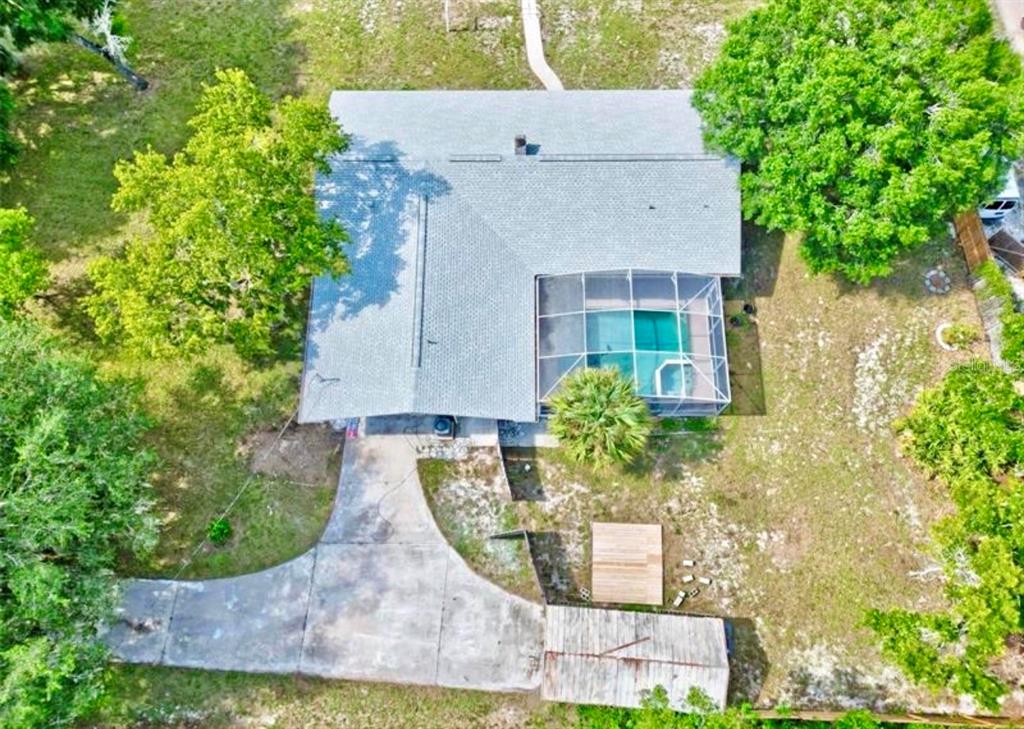 An aerial view shows a house with a screened-in pool, a driveway, and surrounding trees — 2831 ASCOT LANE, DELTONA, FL