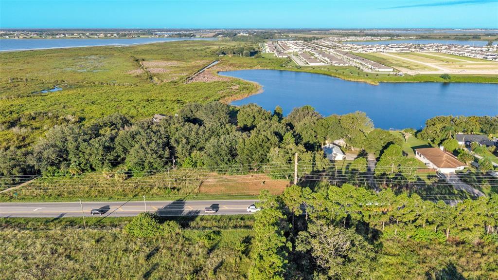 An aerial view shows a vacant lot bordered by a road, trees, and a lake — HWY 557, LAKE ALFRED, FL