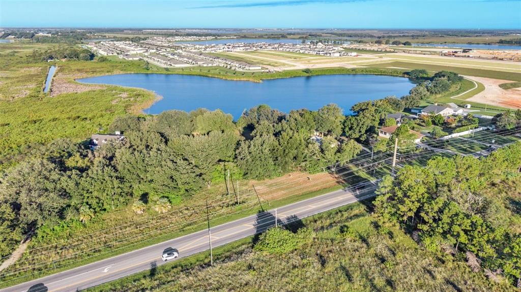 An aerial view shows a road, a large pond, and a residential neighborhood in the distance — HWY 557, LAKE ALFRED, FL