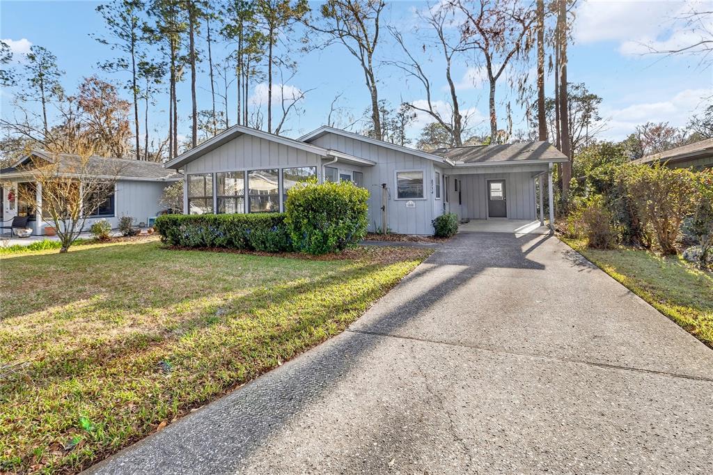 A gray single-story house features a screened-in porch, a concrete driveway, and a carport — 8754 NW 37TH CIRCLE, GAINESVILLE, FL