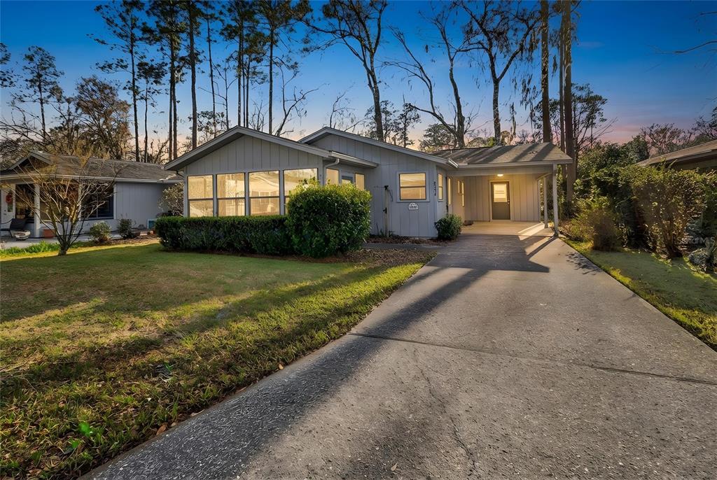 A single-story gray house with a concrete driveway, carport, and a large front window — 8754 NW 37TH CIRCLE, GAINESVILLE, FL