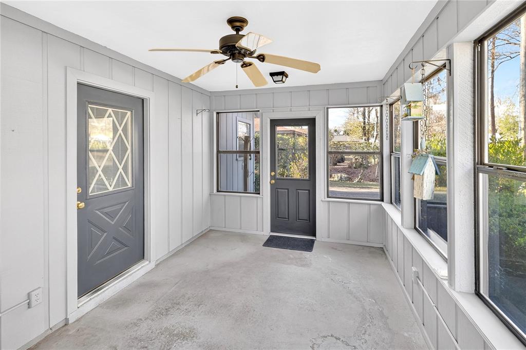 A sunroom with gray paneled walls, a concrete floor, a ceiling fan, and two doors — 8754 NW 37TH CIRCLE, GAINESVILLE, FL