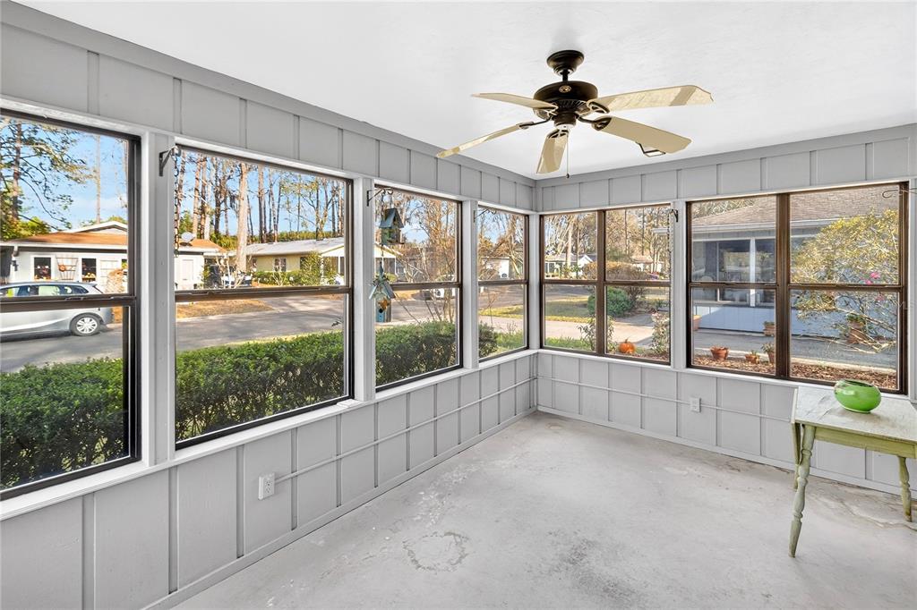 A sunroom with light gray paneled walls, a ceiling fan, and large windows overlooking a street — 8754 NW 37TH CIRCLE, GAINESVILLE, FL