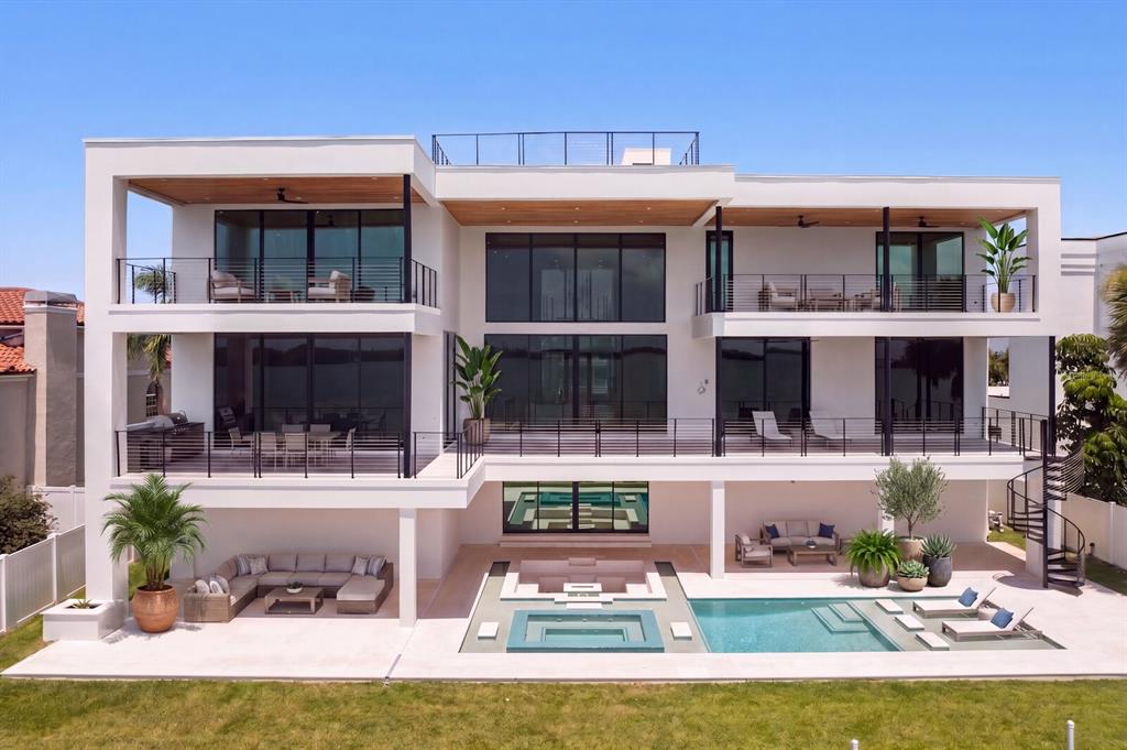 A modern three-story waterfront home features multiple balconies, a swimming pool, and a patio area — 114 SANDS POINT DRIVE, TIERRA VERDE, FL