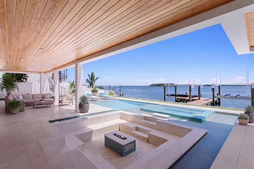 A covered patio features a sunken fire pit lounge area overlooking a pool and bay — 114 SANDS POINT DRIVE, TIERRA VERDE, FL