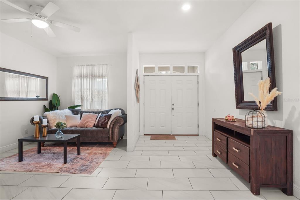 A bright entryway features white tile floors, a dark wood console table, and a seating area — 16626 BEARLE ROAD, ORLANDO, FL