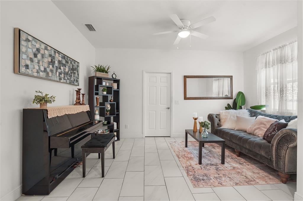 A living room features white tile floors, a black piano, and a grey tufted sofa — 16626 BEARLE ROAD, ORLANDO, FL