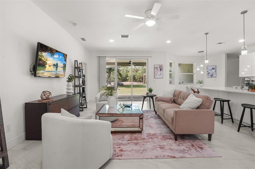 A bright living room features a pink sofa, white armchairs, and a glass coffee table — 16626 BEARLE ROAD, ORLANDO, FL