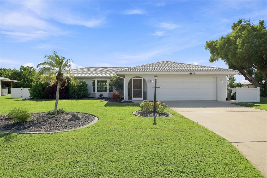 A single-story house with a white garage, a palm tree, and a grassy front yard — 302 DEGAS DRIVE, NOKOMIS, FL