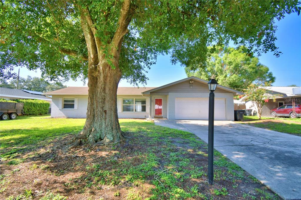 A single-story house with a brick facade, a large front tree, and a concrete driveway — 153 BROWNING CIR, WINTER HAVEN, FL