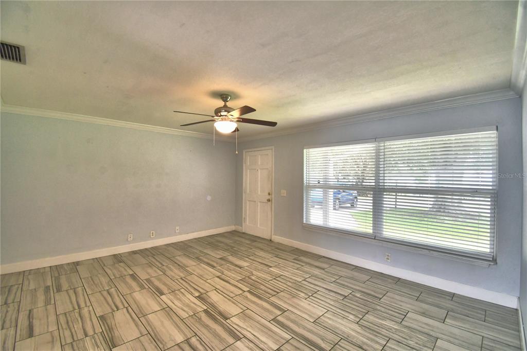 An empty room with light blue walls, wood-look tile flooring, a ceiling fan, and windows — 153 BROWNING CIR, WINTER HAVEN, FL