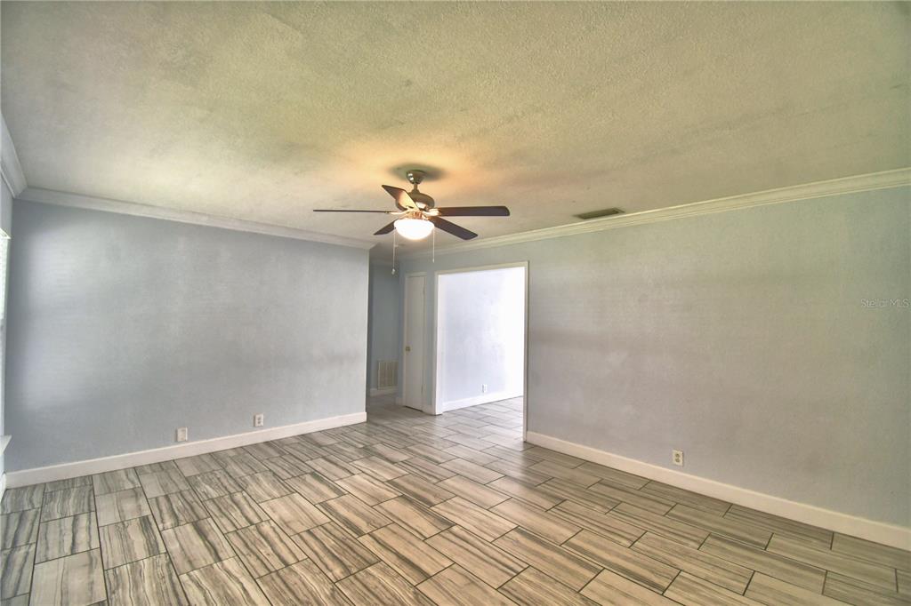 An empty room features light blue walls, wood-look tile flooring, and a ceiling fan — 153 BROWNING CIR, WINTER HAVEN, FL