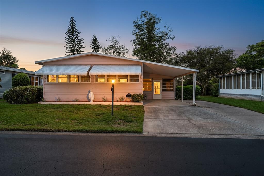 A single-story pink house with a carport and white awnings sits along a paved street — 2542 LONGPINE LANE, ST CLOUD, FL