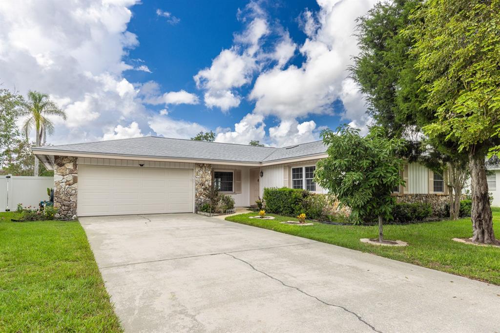 A single-story house with a stone facade, white siding, and a concrete driveway — 116 BEAUFORT DRIVE, LONGWOOD, FL
