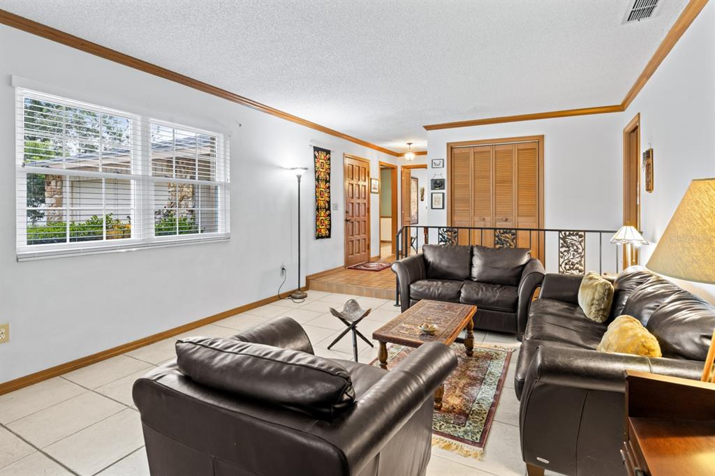 A living room features tile flooring, leather furniture, a wooden coffee table, and a raised entryway — 116 BEAUFORT DRIVE, LONGWOOD, FL