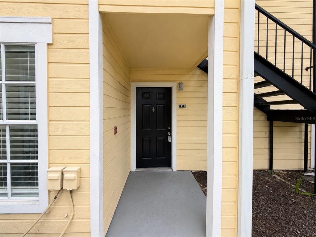 A yellow-sided building exterior features a black front door with the number 1918 — 1057 S HIAWASSEE ROAD UNIT 1918, ORLANDO, FL
