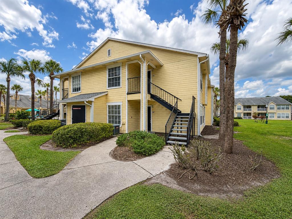 A two-story yellow apartment building features an exterior staircase and a concrete walkway — 1057 S HIAWASSEE ROAD UNIT 1918, ORLANDO, FL
