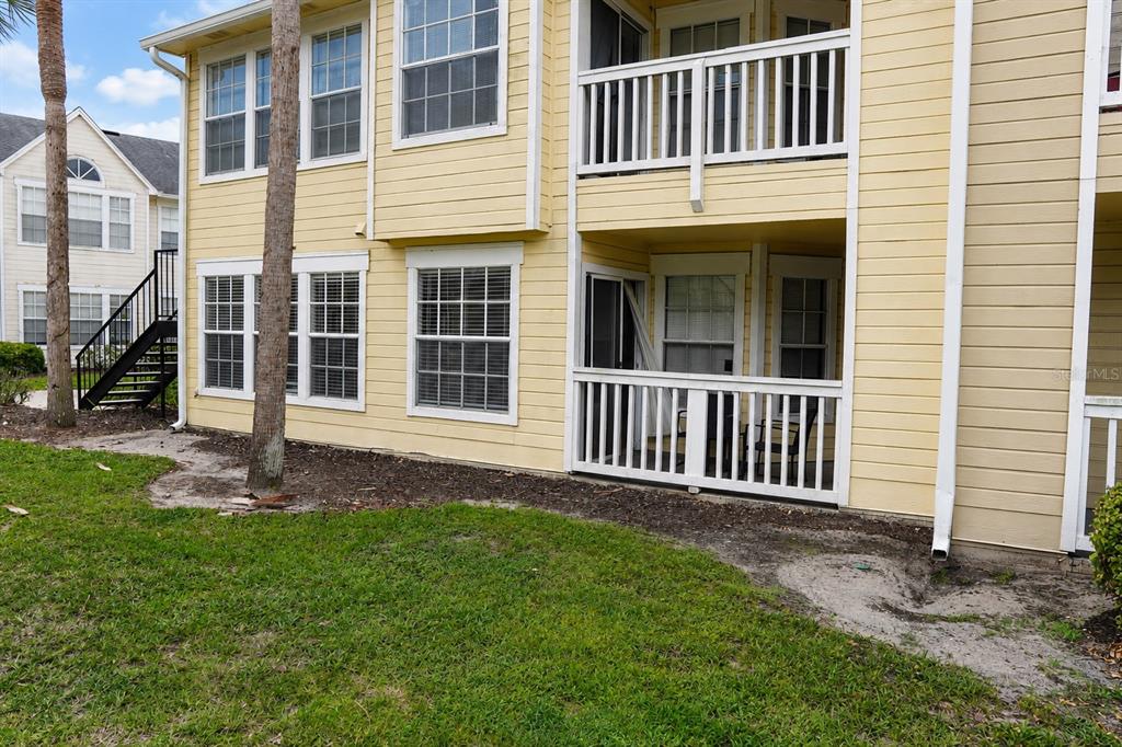 Exterior view of a yellow two-story apartment building with a ground-floor patio and balcony — 1057 S HIAWASSEE ROAD UNIT 1918, ORLANDO, FL