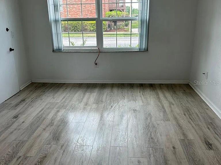 An empty room features light wood-look flooring, white walls, and a window with vertical blinds — 1920 E EDGEWOOD DRIVE UNIT K9, LAKELAND, FL