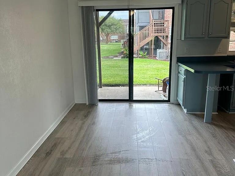 A dining area with wood-look tile flooring features a sliding glass door leading to a patio — 1920 E EDGEWOOD DRIVE UNIT K9, LAKELAND, FL