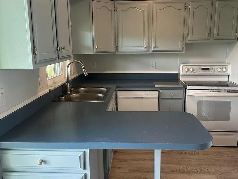 A kitchen features gray cabinets, a blue countertop, a double sink, and a white stove — 1920 E EDGEWOOD DRIVE UNIT K9, LAKELAND, FL