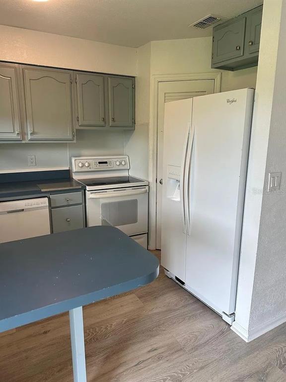 A kitchen features gray cabinets, a white stove, a white refrigerator, and a blue countertop — 1920 E EDGEWOOD DRIVE UNIT K9, LAKELAND, FL
