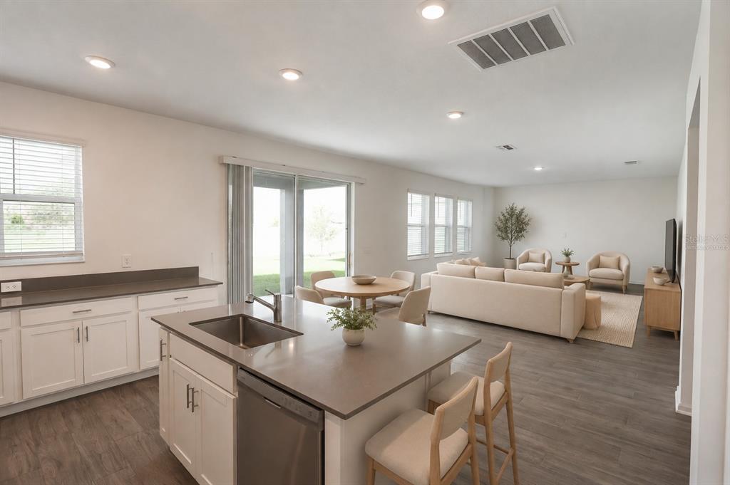 A kitchen with a center island and stainless steel appliances opens into a living area — 2587 RUNNERS CIRCLE, CLERMONT, FL