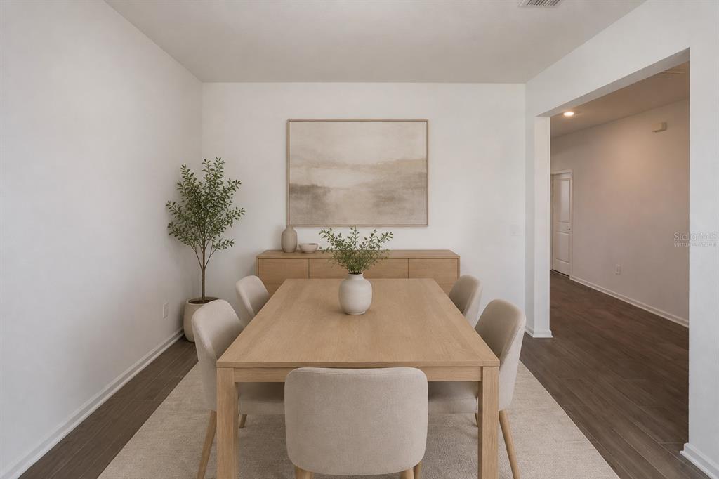A dining room features a light wood table, upholstered chairs, a sideboard, and wall art — 2587 RUNNERS CIRCLE, CLERMONT, FL