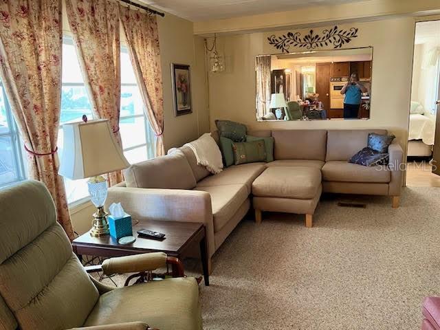 A living room features a beige sectional sofa, a recliner, and a lamp on a table — 3405 LANARK DRIVE, HOLIDAY, FL