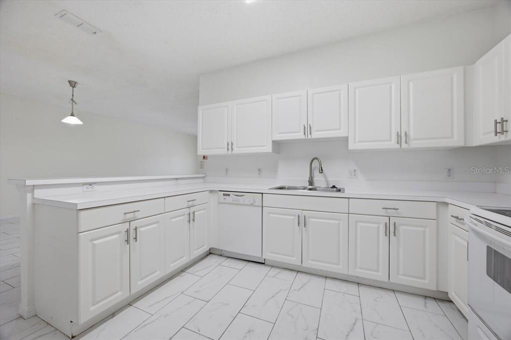 A kitchen with white cabinets, white countertops, and white tile flooring — 3166 SUN LAKE COURT UNIT B, KISSIMMEE, FL
