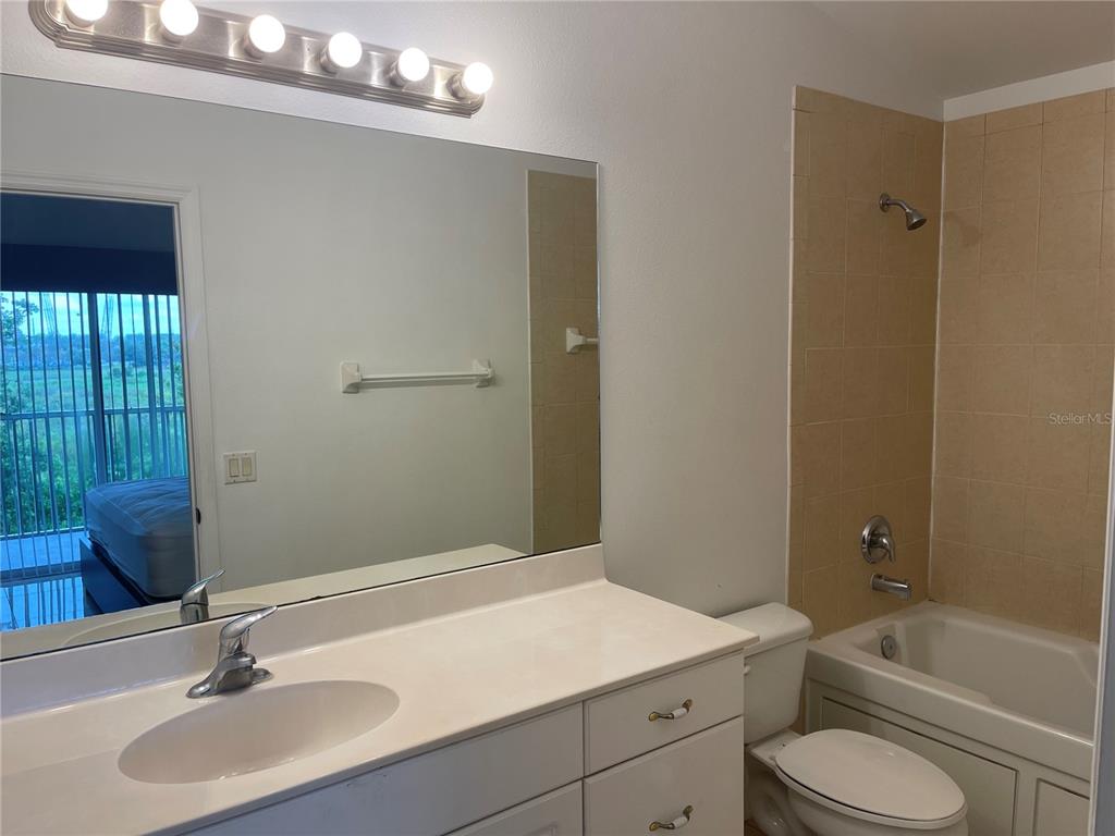 A bathroom features a white vanity, a large mirror, and a beige tiled shower-tub combo — 3166 SUN LAKE COURT UNIT B, KISSIMMEE, FL