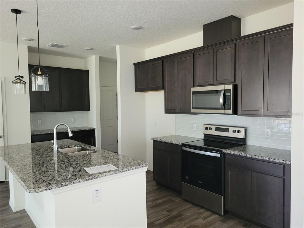 A kitchen features dark wood cabinets, granite countertops, stainless steel appliances, and a central island — 780 CONSUMER STREET SE, PALM BAY, FL