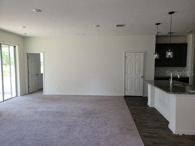 A living area with carpeted flooring, a kitchen island, and two interior doors — 780 CONSUMER STREET SE, PALM BAY, FL